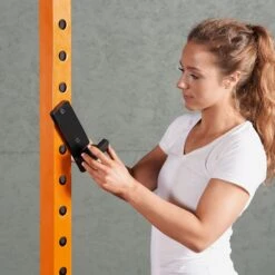 Mirafit M220 Squat Rack -Fitness Promotion Store woman adding J Cups to Mirafit M220 Squat Rack in orange